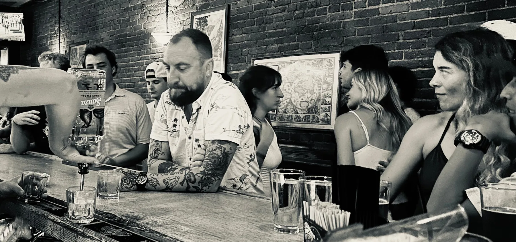 Aaron Hutten sitting at a crowded bar while a bartender pours a drink